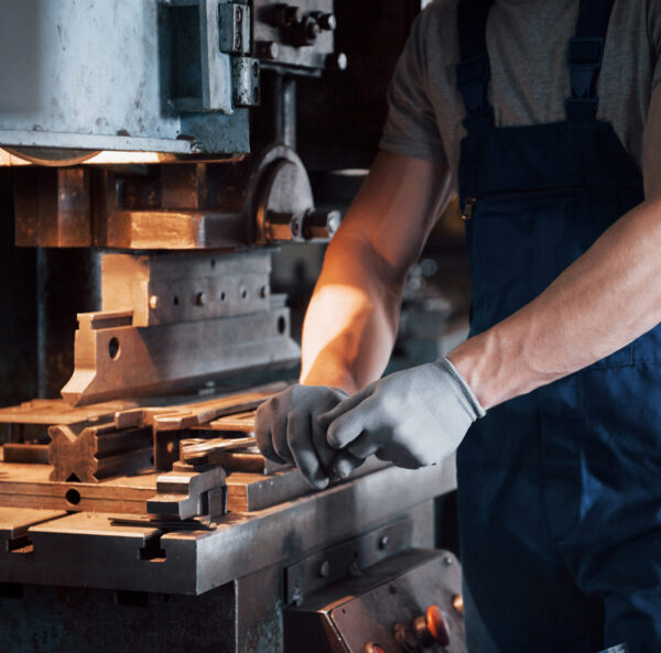 Portrait of a young worker in a hard hat at a large metalworking plant. The engineer serves the machines and manufactures parts for gas equipment.